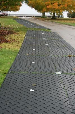 Double track of ground protection mats laid over lawn to stop vehicles damaging the grass