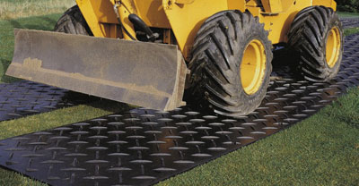 Digger driving on grass where ground protection mats are placed