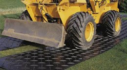 Track mats with a yellow excavator driving over them.